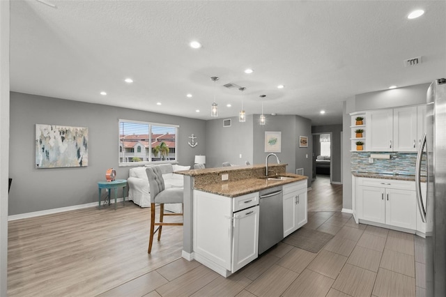 kitchen with white cabinets, hanging light fixtures, stainless steel appliances, open shelves, and a sink