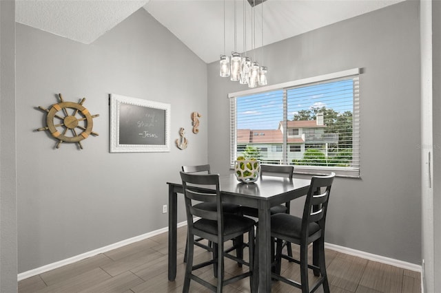 dining room featuring lofted ceiling, dark wood-type flooring, and baseboards