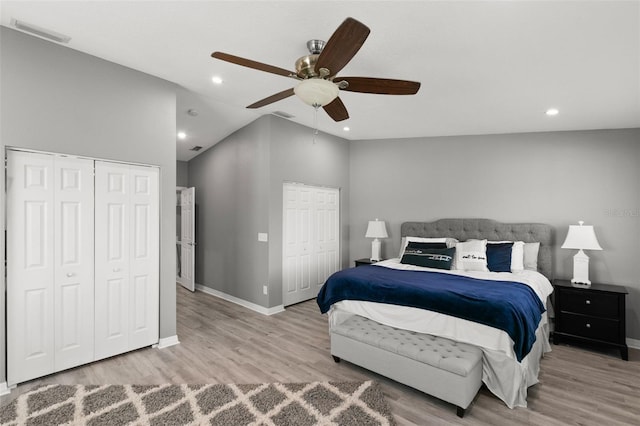 bedroom featuring visible vents, vaulted ceiling, multiple closets, and wood finished floors