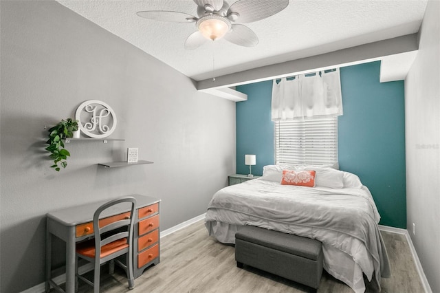 bedroom featuring light wood finished floors, ceiling fan, baseboards, and a textured ceiling