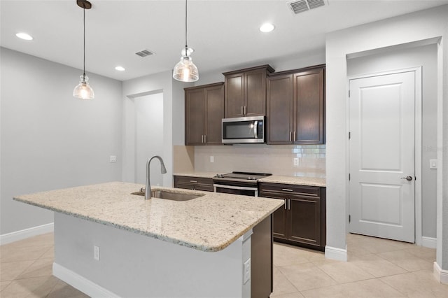 kitchen with decorative light fixtures, stainless steel appliances, visible vents, a kitchen island with sink, and a sink