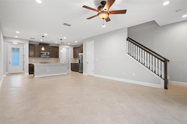 unfurnished living room with baseboards, visible vents, a ceiling fan, stairs, and recessed lighting