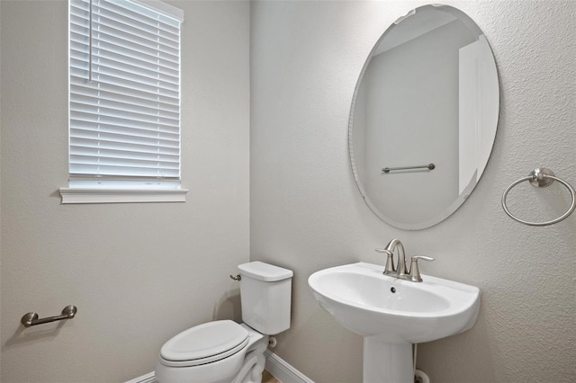 half bathroom featuring toilet and baseboards