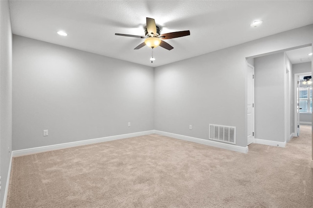 unfurnished room with light carpet, ceiling fan, visible vents, and baseboards