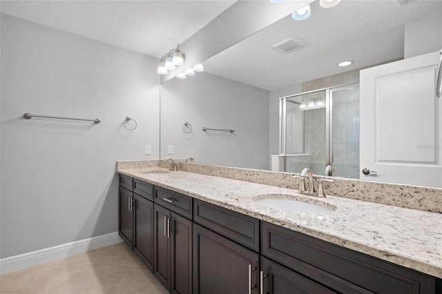 bathroom featuring double vanity, tile patterned flooring, a shower stall, and a sink