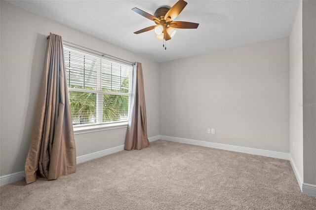 spare room with light colored carpet, ceiling fan, and baseboards