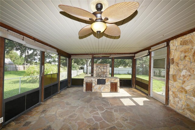 unfurnished sunroom featuring a wealth of natural light, wooden ceiling, and ceiling fan