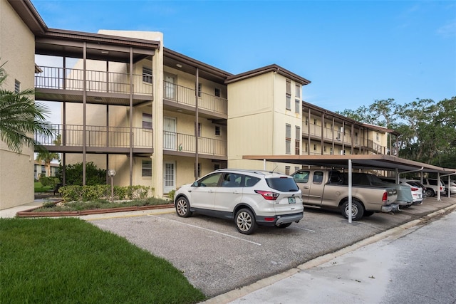 view of building exterior featuring covered and uncovered parking