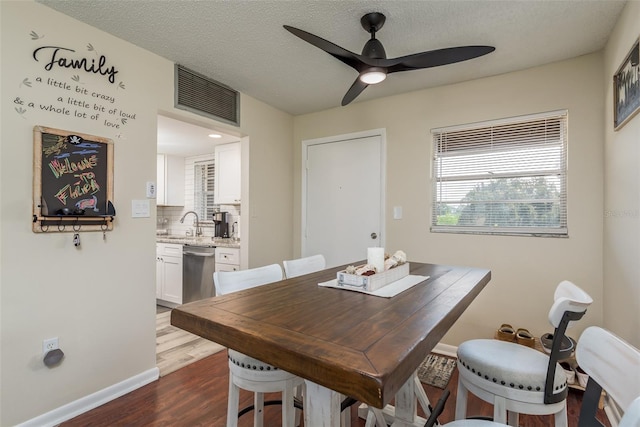 dining area featuring ceiling fan, dark wood-type flooring, sink, and a textured ceiling