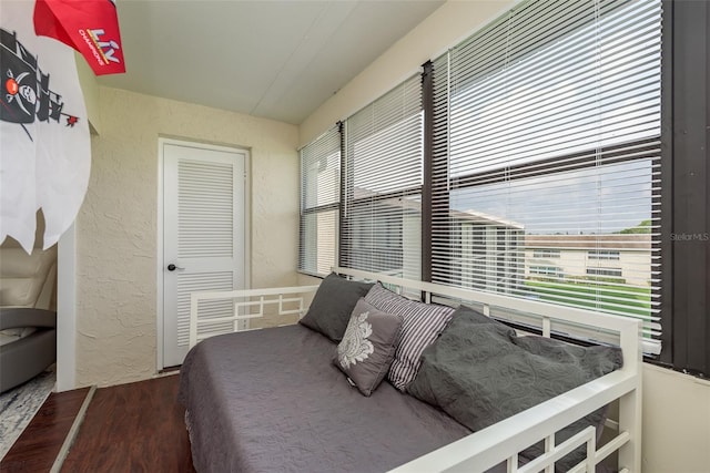 bedroom with a closet, hardwood / wood-style flooring, and multiple windows