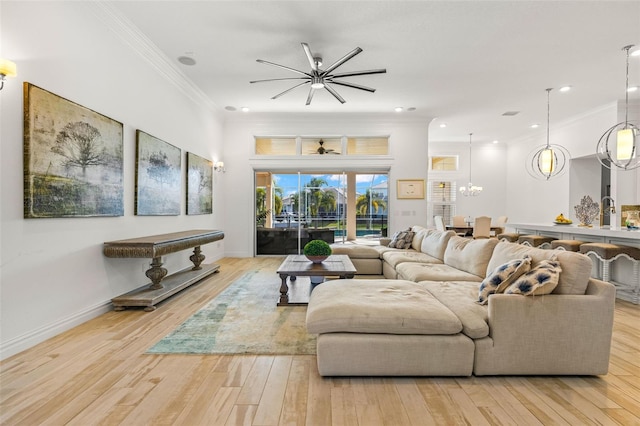 living room featuring crown molding, light wood-type flooring, and ceiling fan with notable chandelier