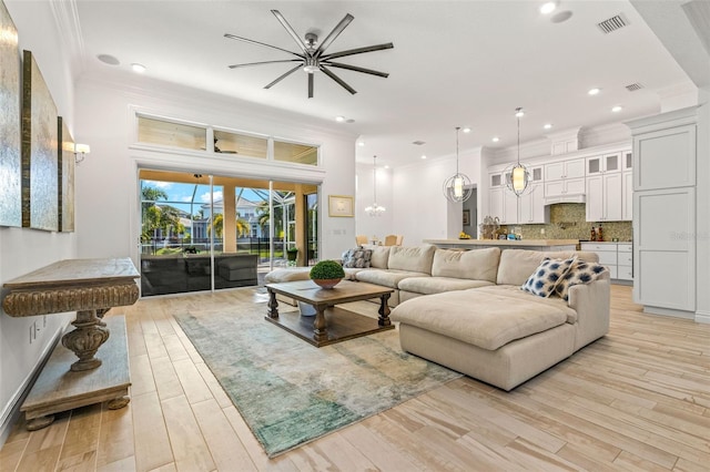 living room featuring ceiling fan, crown molding, and light wood-type flooring