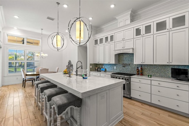 kitchen featuring tasteful backsplash, light wood-type flooring, a breakfast bar, and high end stove