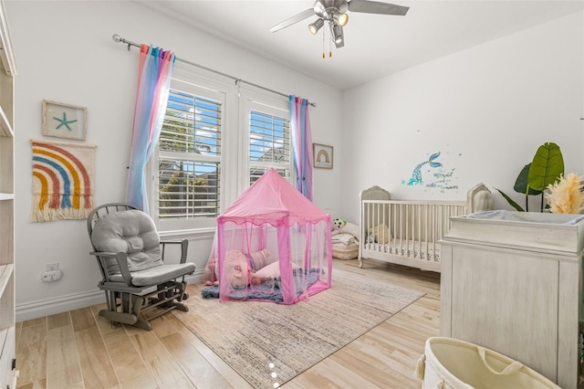 bedroom with light hardwood / wood-style flooring, a crib, and ceiling fan