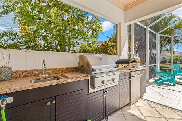 view of patio featuring glass enclosure, an outdoor kitchen, sink, and a grill