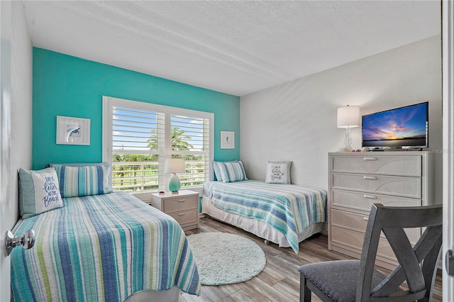 bedroom with a textured ceiling and light wood-type flooring