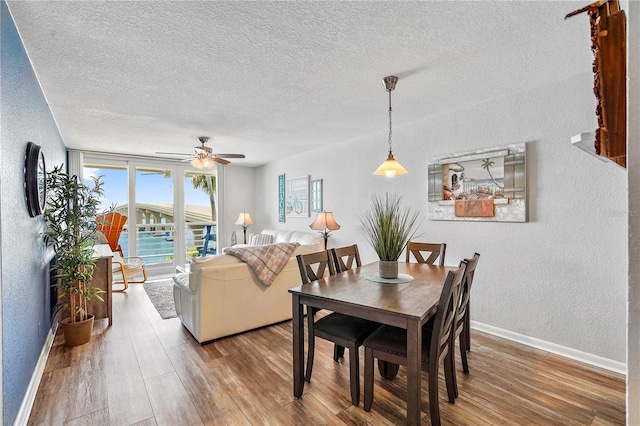 dining area with ceiling fan, hardwood / wood-style floors, and a textured ceiling