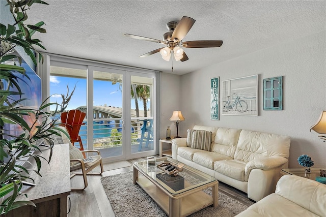 living room featuring ceiling fan, hardwood / wood-style flooring, and a textured ceiling