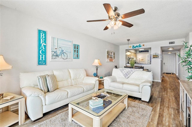 living room with hardwood / wood-style floors, a textured ceiling, and ceiling fan