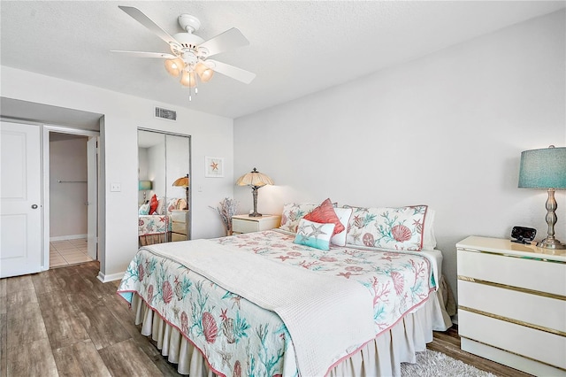 bedroom with ceiling fan, hardwood / wood-style flooring, a closet, and a textured ceiling