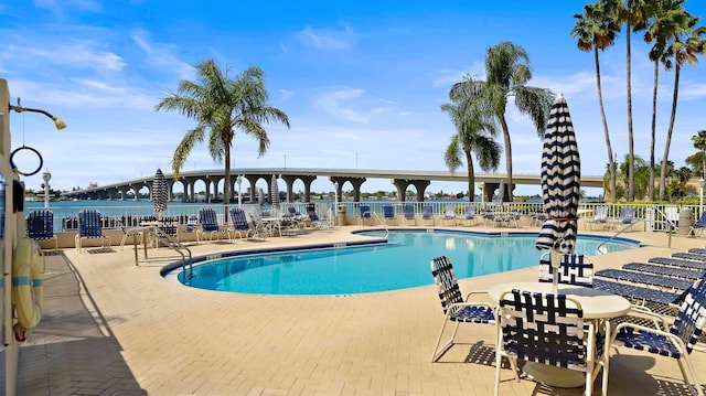 view of pool featuring a water view and a patio area