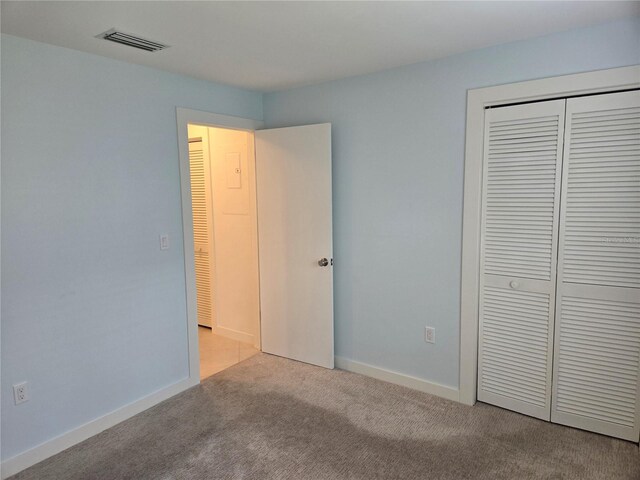 unfurnished bedroom with light colored carpet and a closet