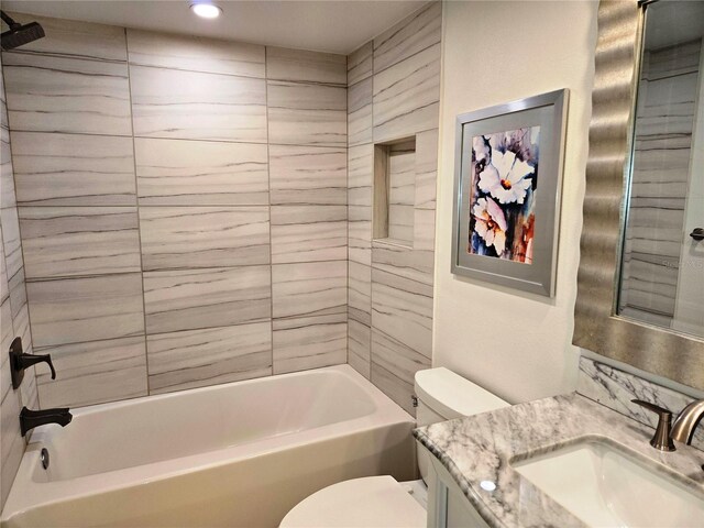 full bathroom with tiled shower / bath, vanity, and toilet