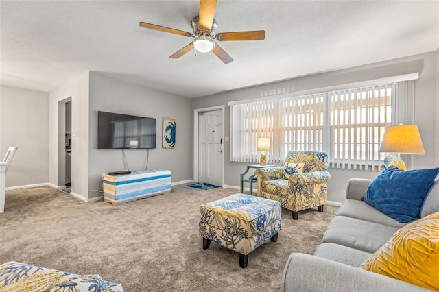 living room with ceiling fan, a textured ceiling, baseboards, and carpet flooring