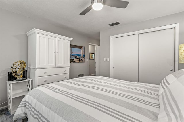 bedroom featuring a closet, visible vents, a ceiling fan, carpet flooring, and a textured ceiling