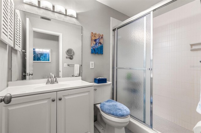 full bathroom with toilet, vanity, a shower stall, and visible vents