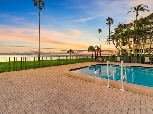 pool at dusk with a patio area