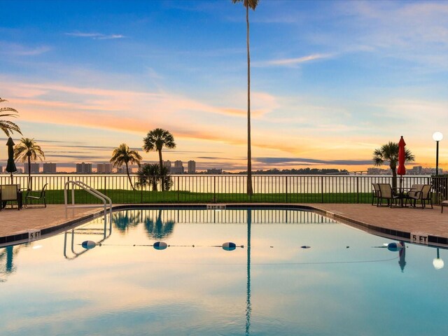 pool at dusk with a patio area