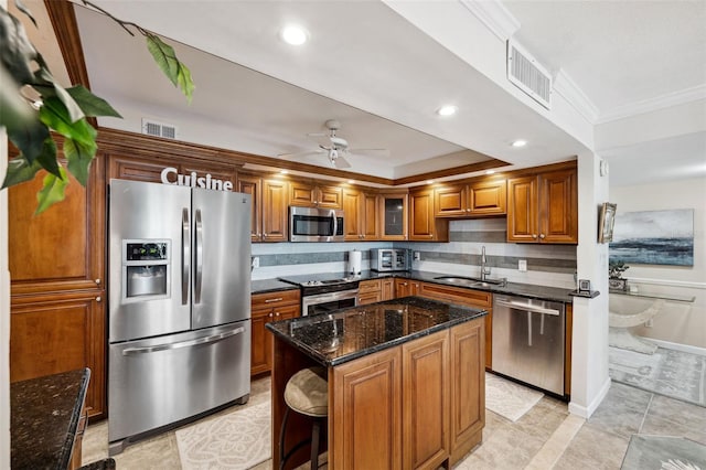 kitchen featuring appliances with stainless steel finishes, sink, dark stone countertops, decorative backsplash, and a center island