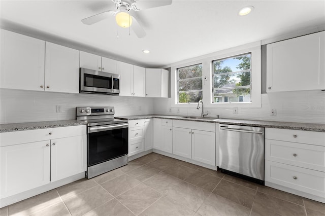 kitchen featuring light stone counters, white cabinets, light tile patterned floors, stainless steel appliances, and sink