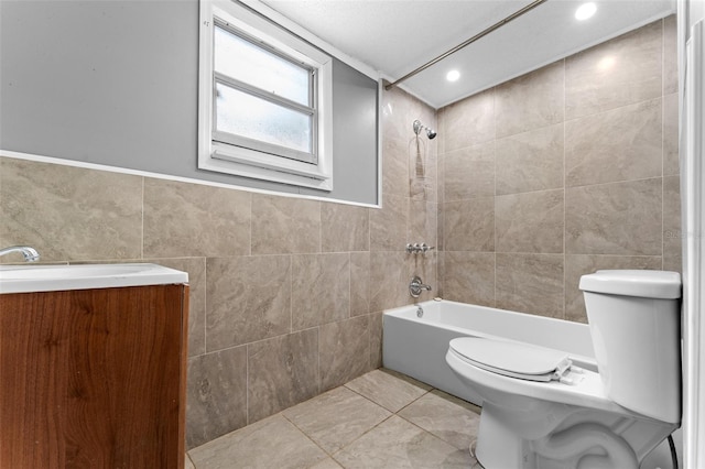 full bathroom with tile walls, tiled shower / bath, toilet, vanity, and tile patterned flooring