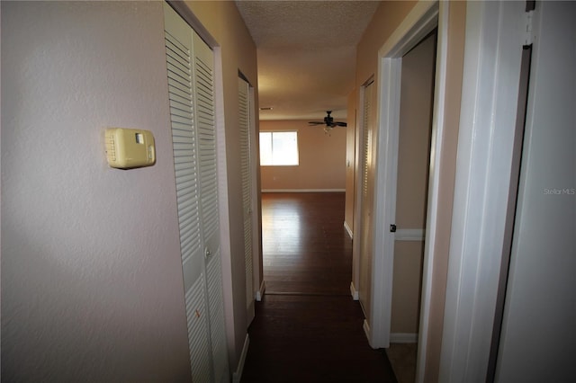 hall with a textured ceiling and dark hardwood / wood-style floors