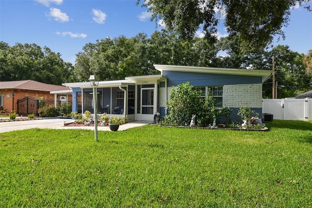 view of front of property featuring cooling unit, a sunroom, and a front lawn