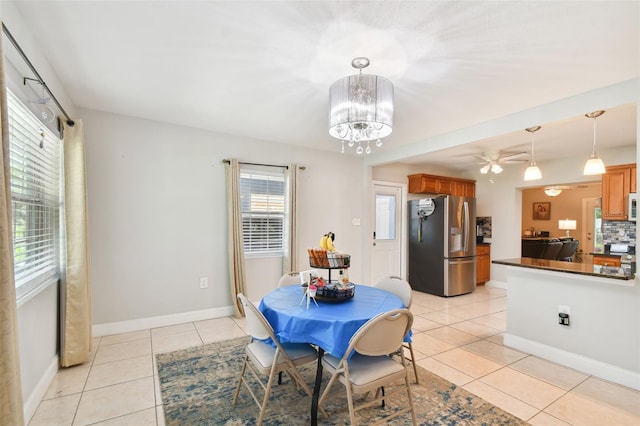 tiled dining area featuring ceiling fan with notable chandelier