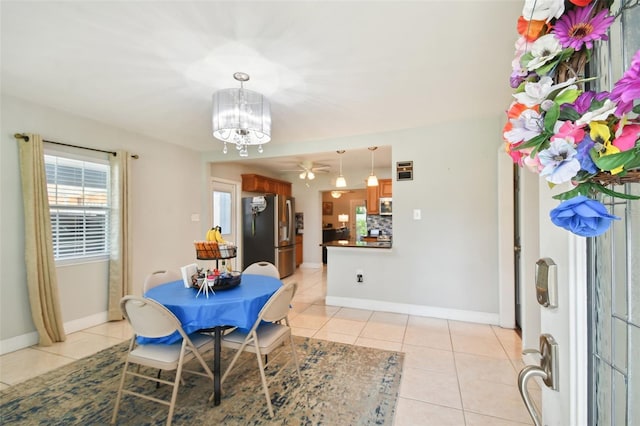 dining area featuring light tile patterned flooring and ceiling fan with notable chandelier