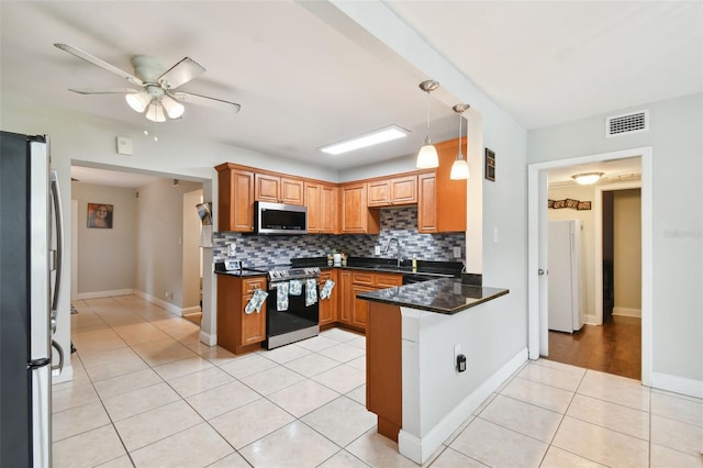 kitchen featuring stainless steel appliances, light tile patterned flooring, decorative backsplash, and kitchen peninsula