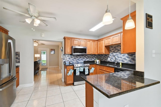 kitchen featuring sink, decorative light fixtures, dark stone counters, kitchen peninsula, and stainless steel appliances