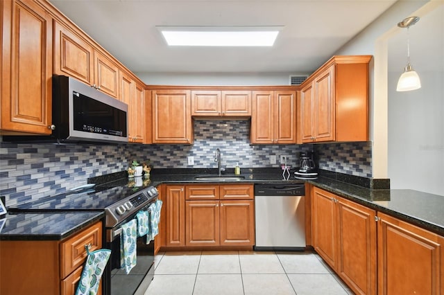 kitchen featuring sink, decorative light fixtures, light tile patterned floors, dark stone counters, and stainless steel appliances