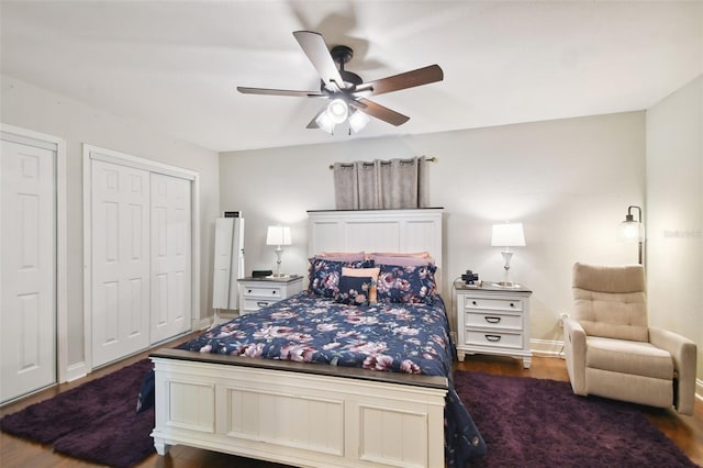 bedroom featuring dark wood-type flooring, two closets, and ceiling fan