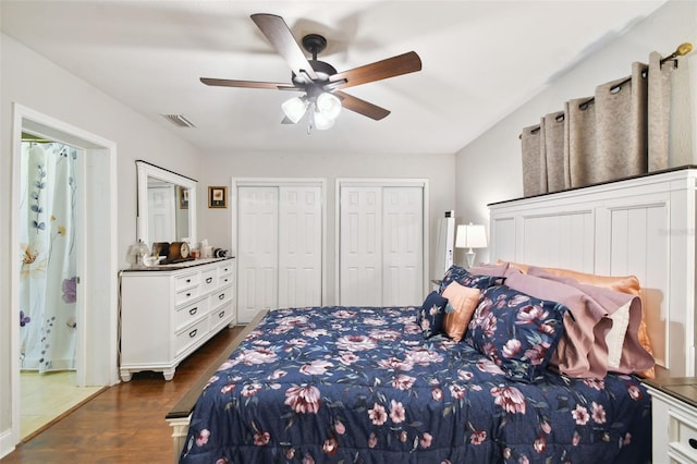 bedroom featuring two closets, dark hardwood / wood-style floors, and ceiling fan