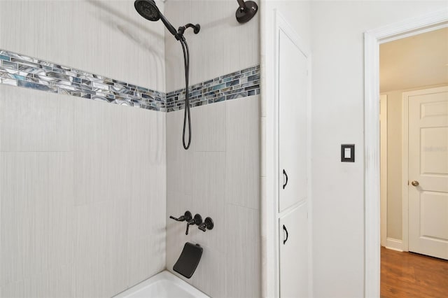 bathroom with hardwood / wood-style flooring and tiled shower / bath combo