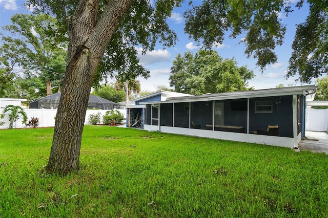 rear view of property featuring a lawn and a sunroom