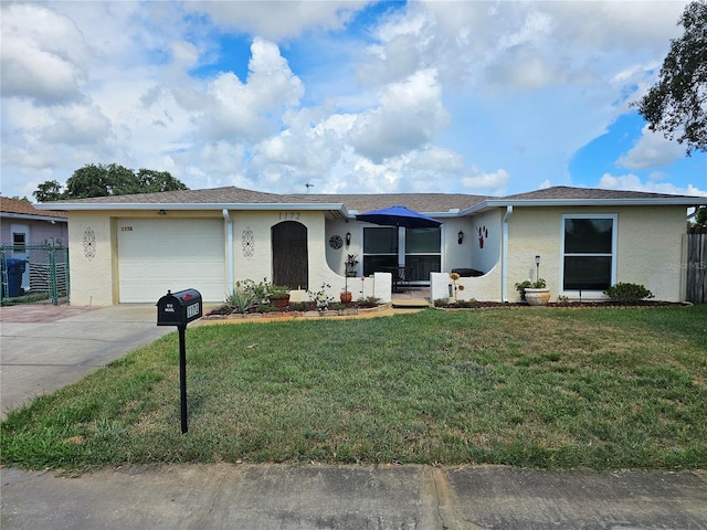 ranch-style home with concrete driveway, a front lawn, fence, and stucco siding