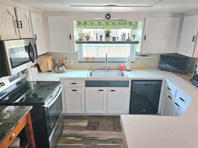 kitchen with light countertops, backsplash, appliances with stainless steel finishes, white cabinetry, and a sink