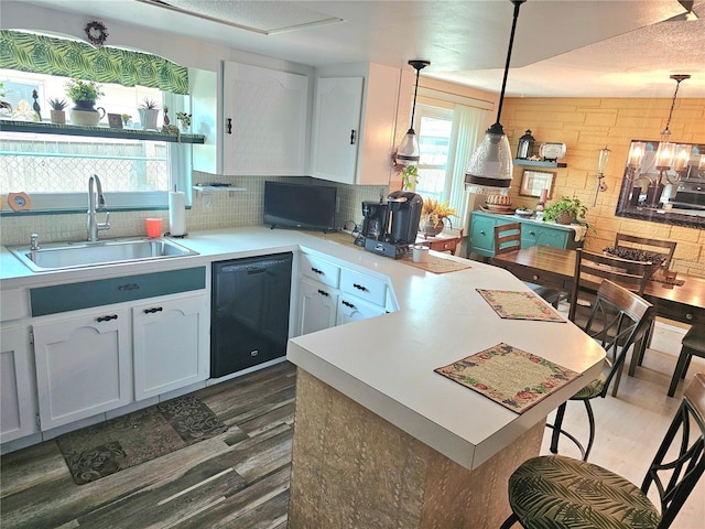 kitchen with dark wood finished floors, light countertops, dishwasher, and a sink