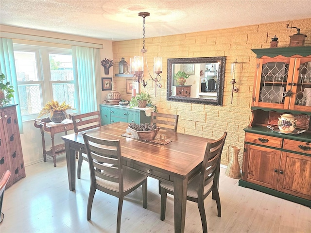 dining room with a textured ceiling, light wood finished floors, baseboards, and an inviting chandelier